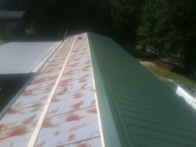 Old rusted panels beside newly installed green metal roofing — Wind Damage Roof Repair by Roofing Brothers in Hooksett