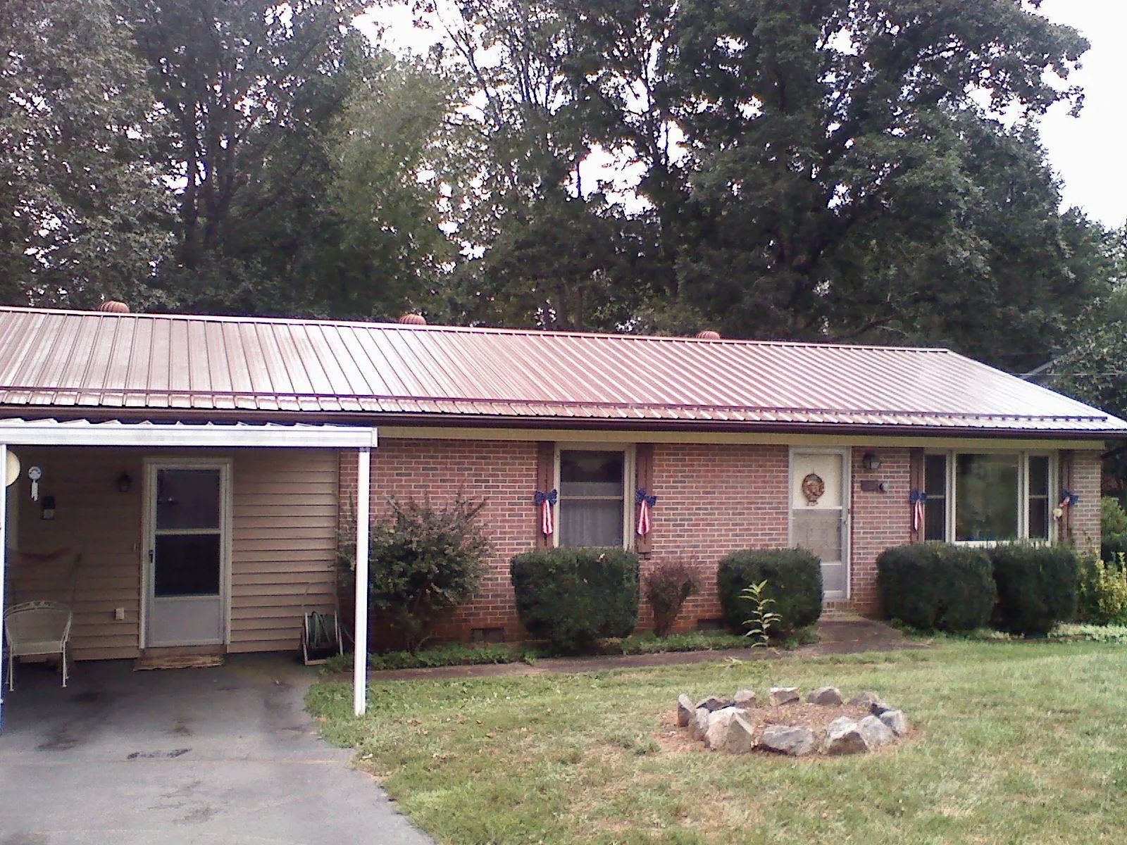 Bronze metal roof and carport on a brick ranch home — Roof Repair work by our crew in Hooksett