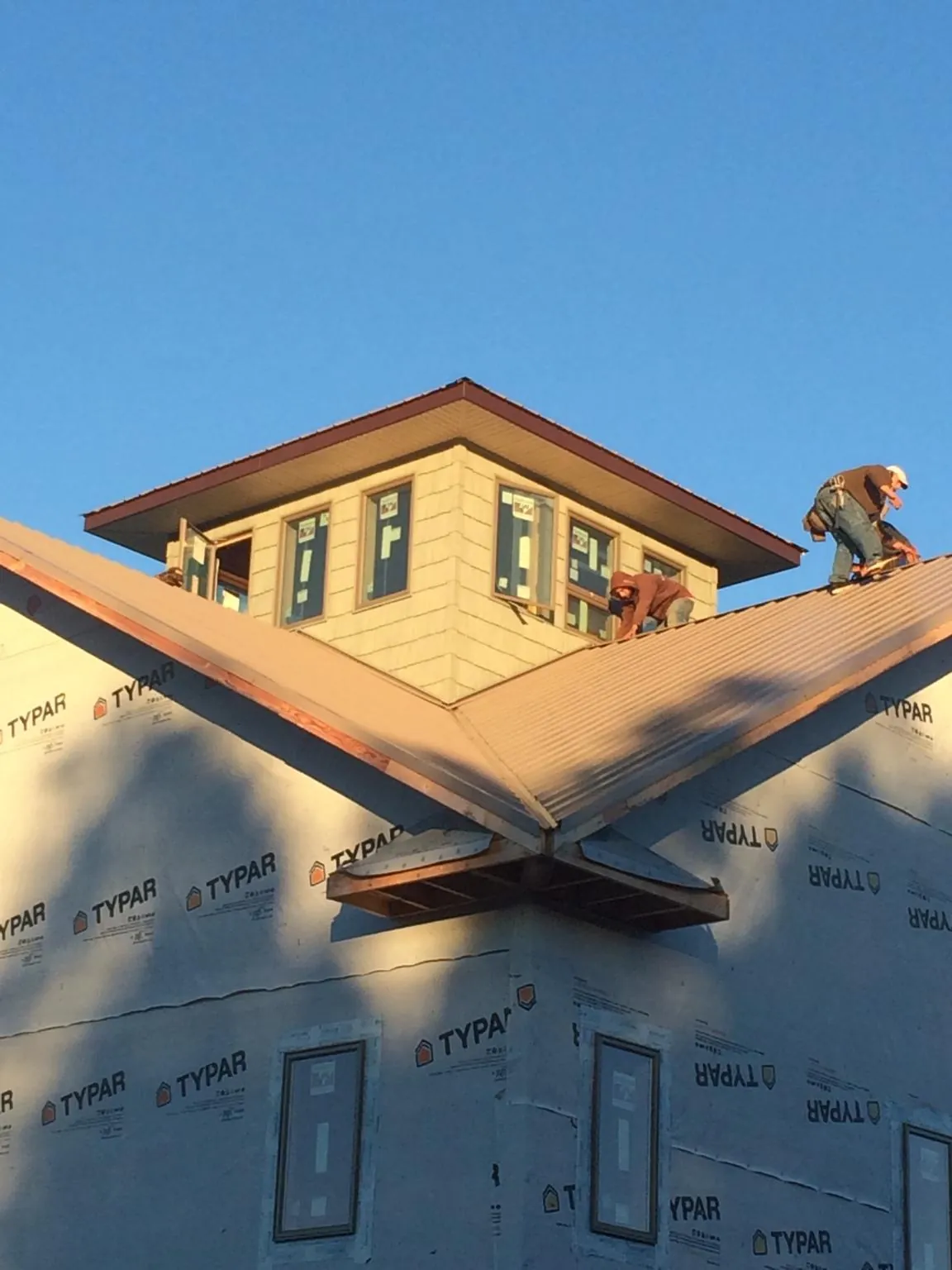 Roofers working around a rooftop cupola on a new metal roof at sunset — Roof Waterproofing in Hooksett by Roofing Brothers